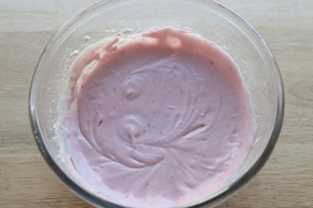 strawberry frosting in a glass bowl to go on the Freshly Milled Valentine's Strawberry Cinnamon Rolls