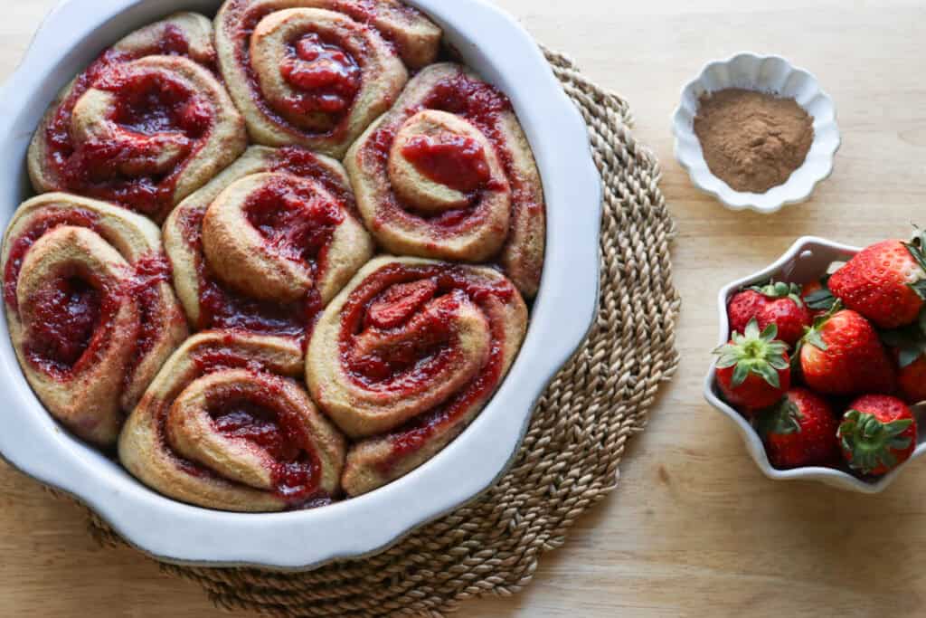 Freshly Milled Valentine's Strawberry Cinnamon Rolls that have been baked with a bowl of strawberries beside them