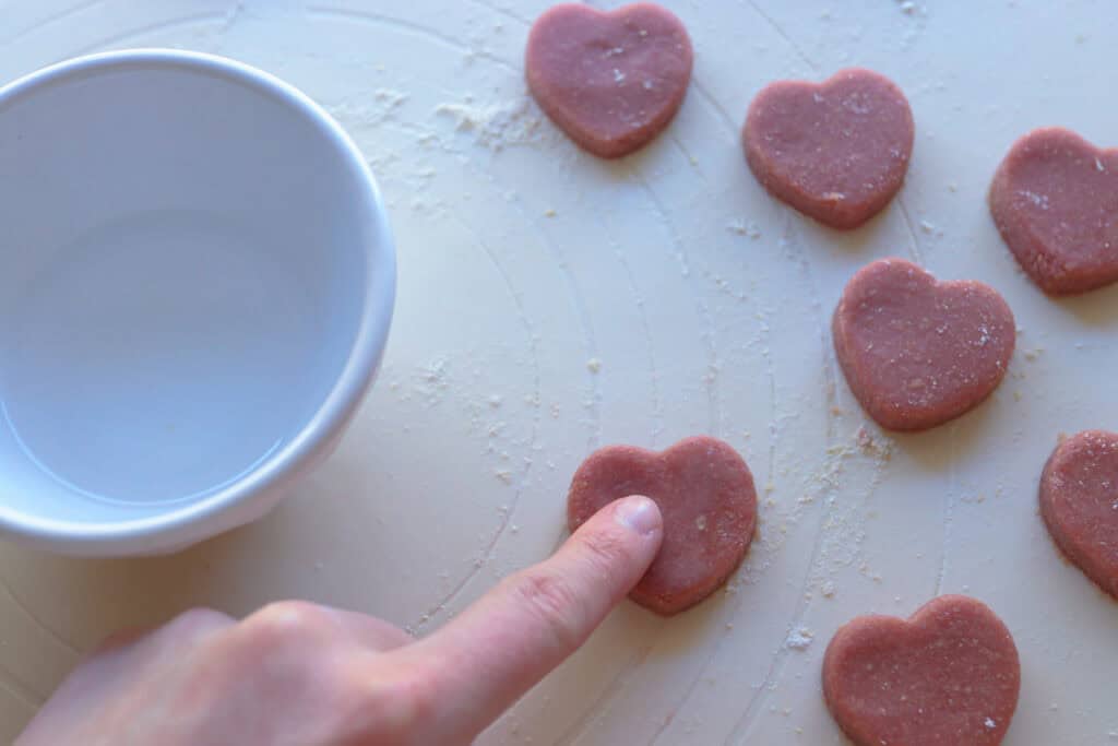 rubbing water on pink hearts to make Freshly Milled Slice and Bake Valentine's Cookies