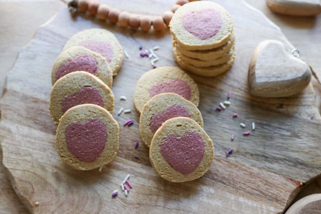 Freshly Milled Slice and Bake Valentine's Cookies on a cutting board with pink and purple sprinkles