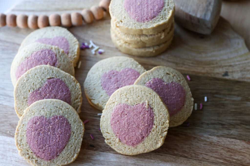 Freshly Milled Slice and Bake Valentine's Cookies with pink hearts in the middle and sprinkles on a wooden board
