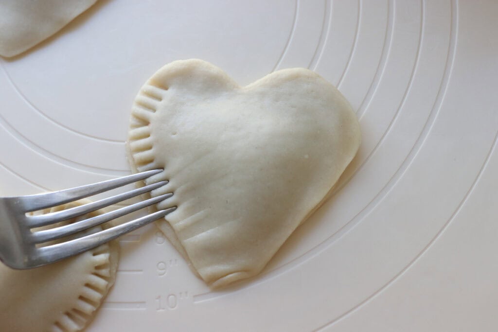 crimping the edges of a Fresh Milled Homemade Valentine's Strawberry Poptart with a fork