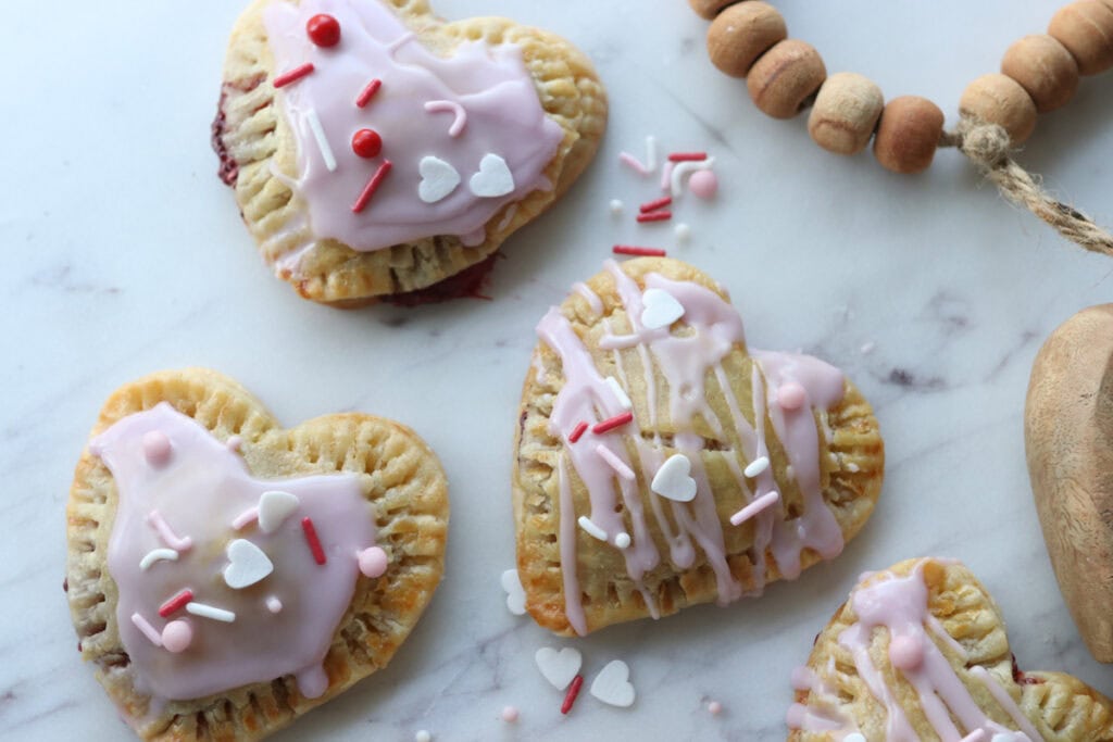 Fresh Milled Homemade Valentine's Strawberry Poptarts on marble with pink icing and sprinkles on top