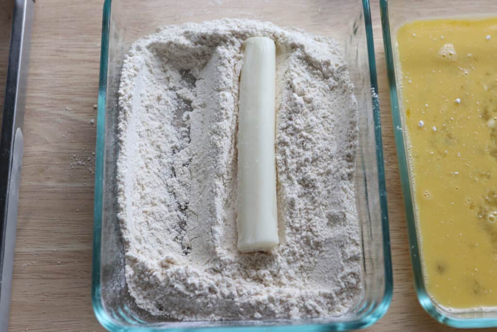 rolling a mozzarella stick in fresh milled flour