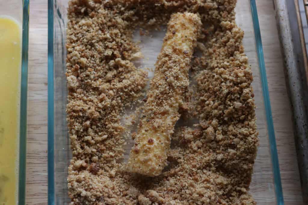 rolling a mozzarella stick in fresh milled breadcrumbs
