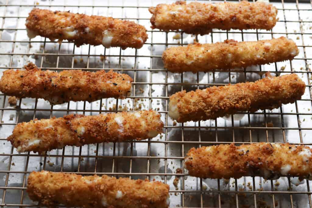 fresh milled mozzarella sticks that have been fried and placed on a cooling rack