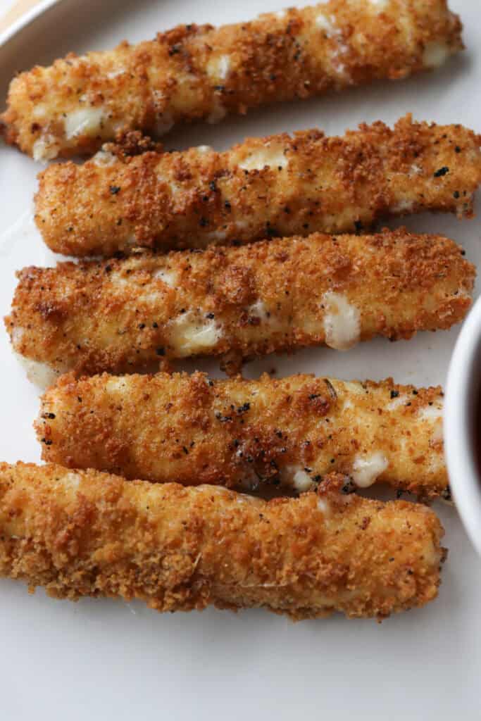fresh milled fried mozzarella sticks with cheese oozing out and herbs