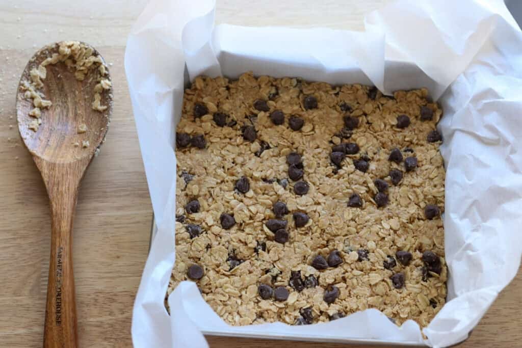 Easy and Delicious Copycat Heavenly Hunk Squares pressed into a pan lined with parchment paper