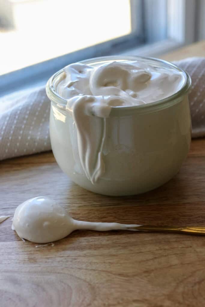 homemade marshmallow fluff in a glass jar with fluff spilling down the side