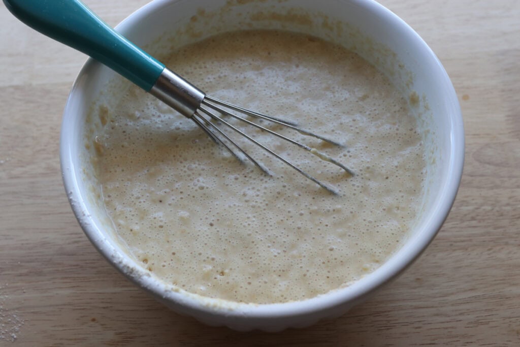 Freshly Milled Fluffy Lemon Blueberry Pancake Batter in a white bowl with a whisk
