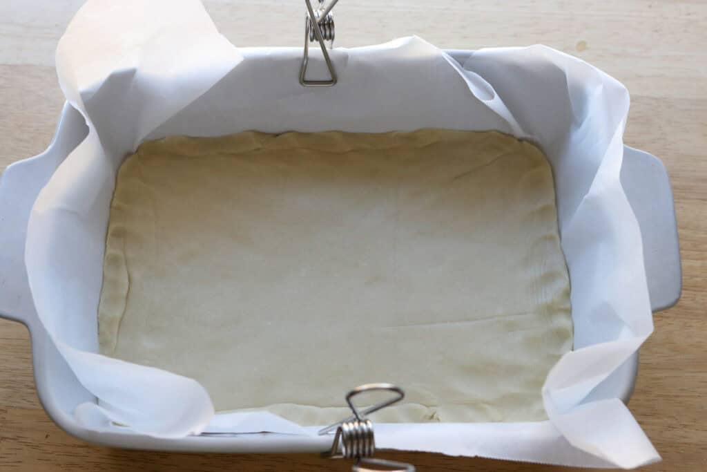 pie crust in a pan with parchment paper to make The Best Blueberry Pie Bars with Fresh Milled Flour