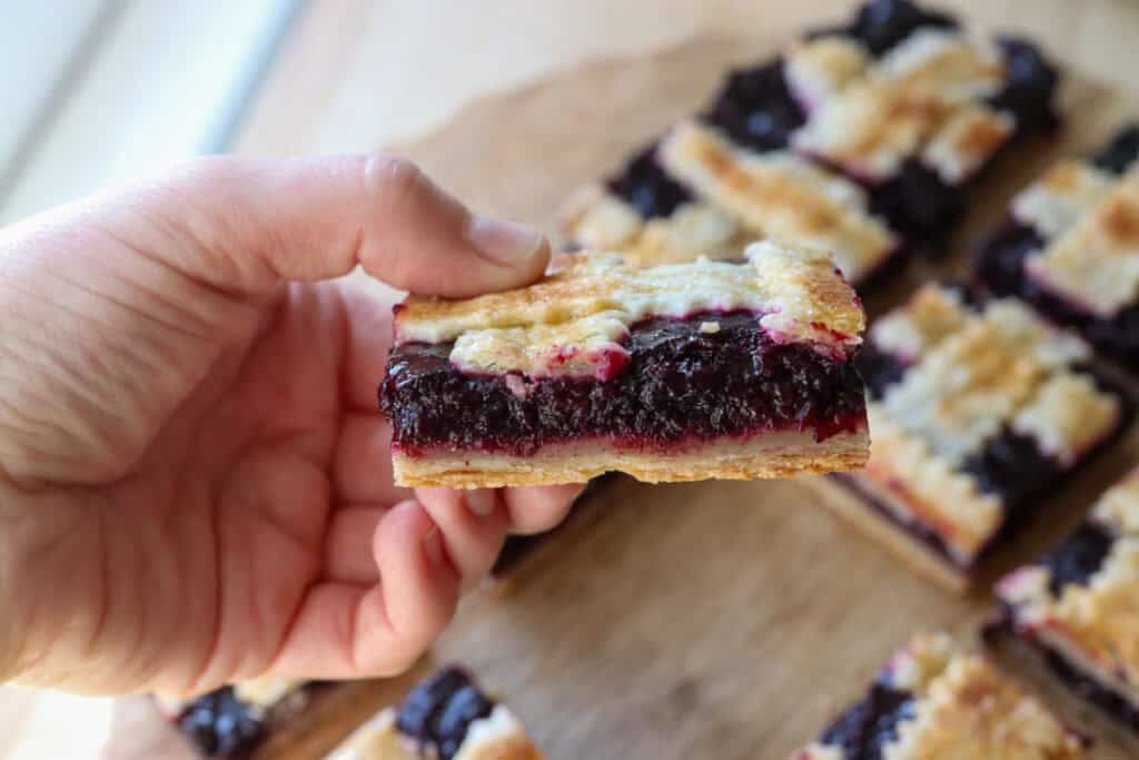 someone holding a freshly milled blueberry pie bar