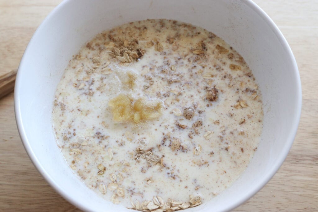milk and applesauce added to a white bowl to make healthy and homemade chai baked oatmeal