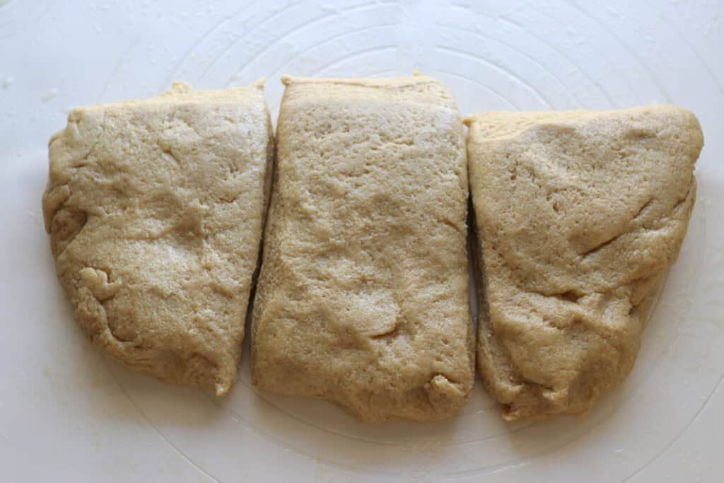 freshly milled braided challah dough divided into 3 pieces