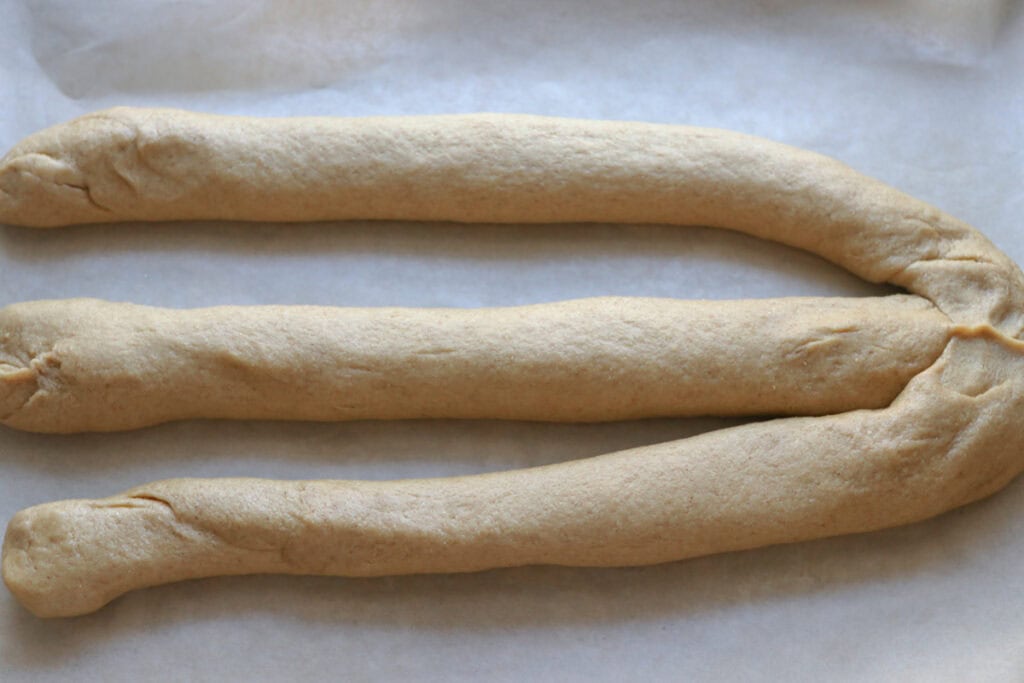 3 strands freshly milled braided challah bread dough that have been attached at one end