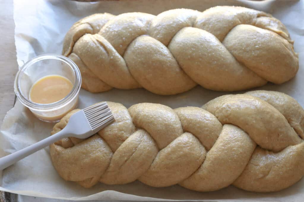 freshly milled braided challah bread that has been brushed with an egg wash