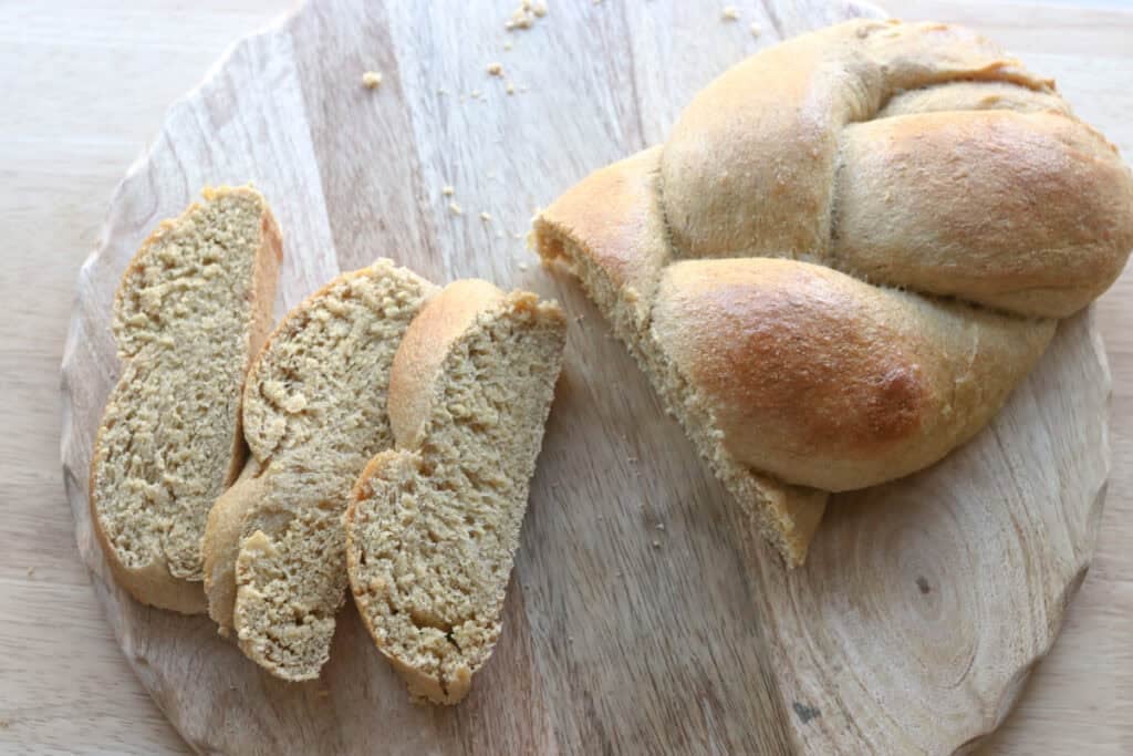 Freshly milled braided challah bread on a cutting board that has been sliced