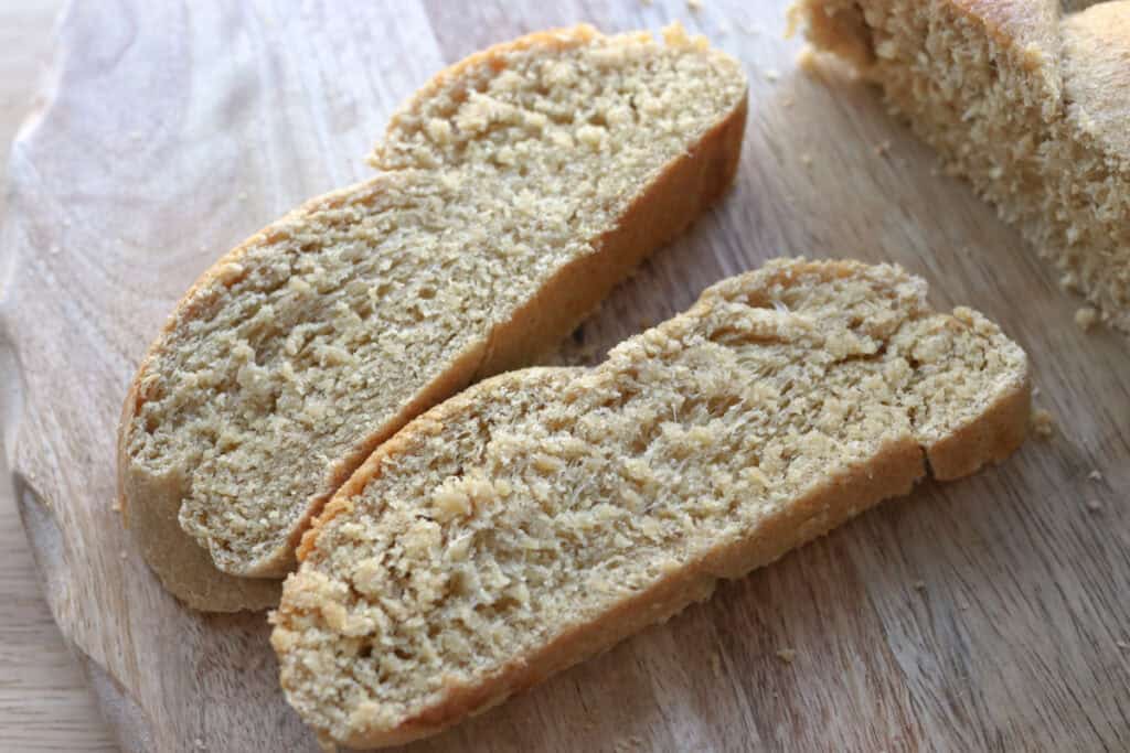 two slices of freshly milled braided challah bread on a wooden board