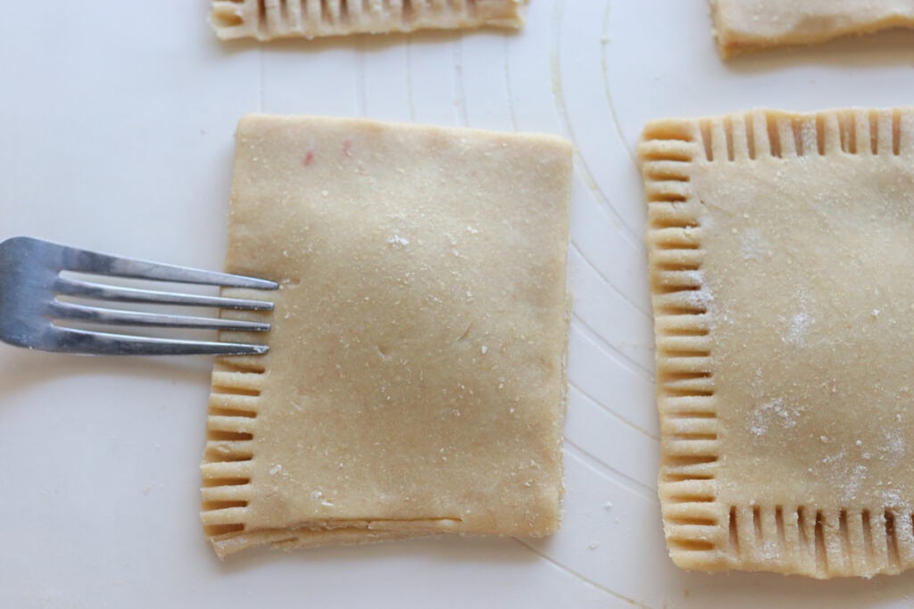 crimping the edges of a freshly milled pop-tart with a fork