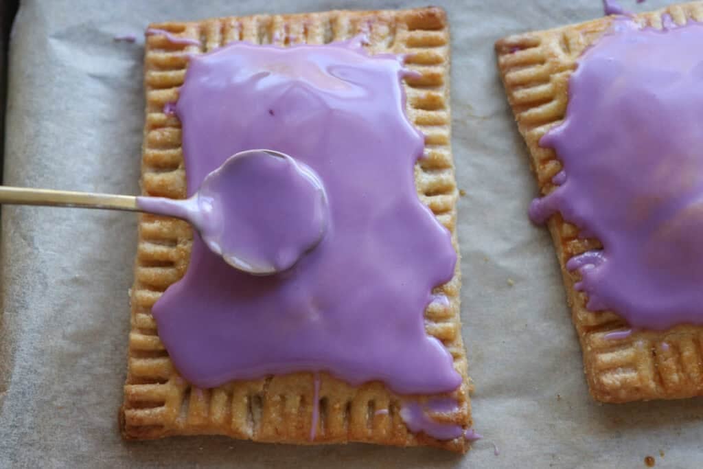 spreading purple icing onto freshly milled homemade wild berry pop-tarts