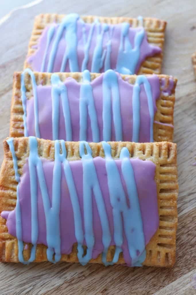 three freshly milled homemade wild berry pop-tarts stacked together with purple icing