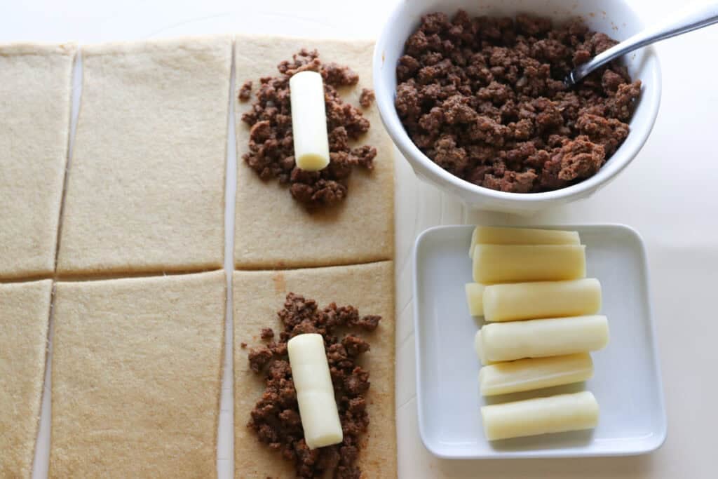ground beef and cheese sticks being placed on fresh milled dough to make fresh milled cheesy taco pockets