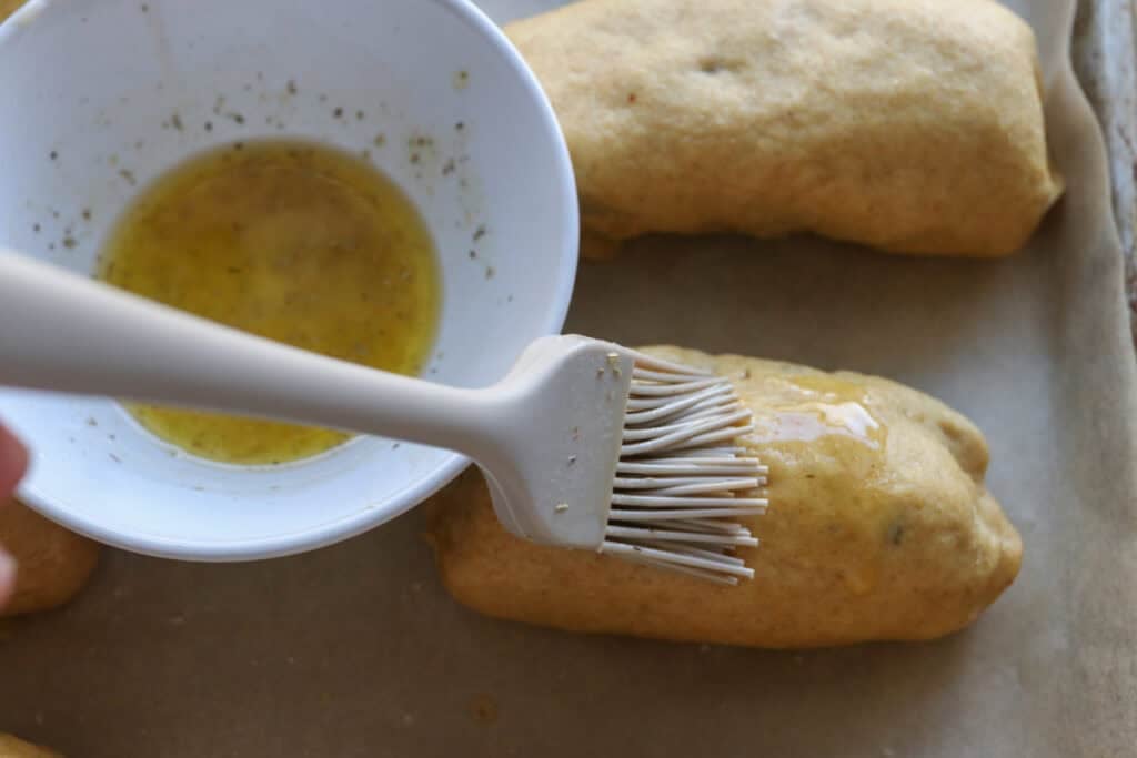 brushing Fresh milled cheesy taco pockets with garlic butter