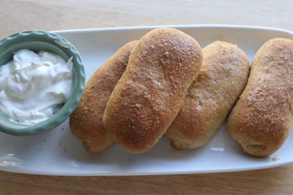 fresh milled cheesy taco pockets on a white plate with sour cream