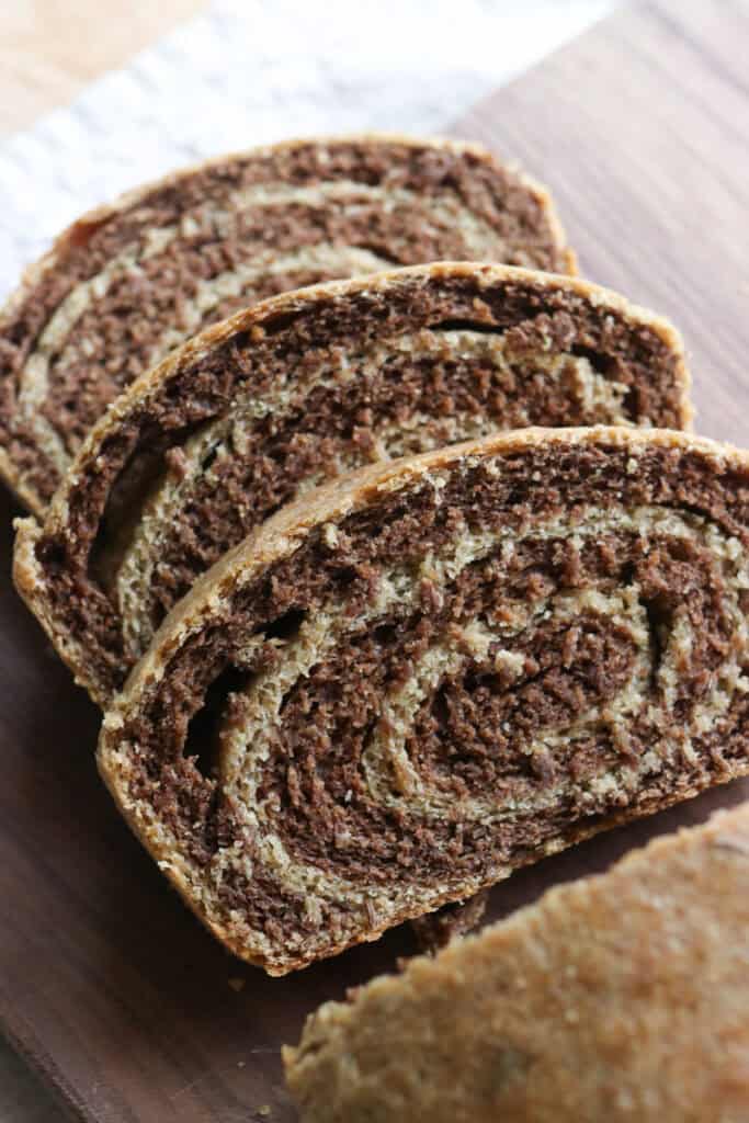 three slices of freshly milled marbled rye bread on a wooden cutting board