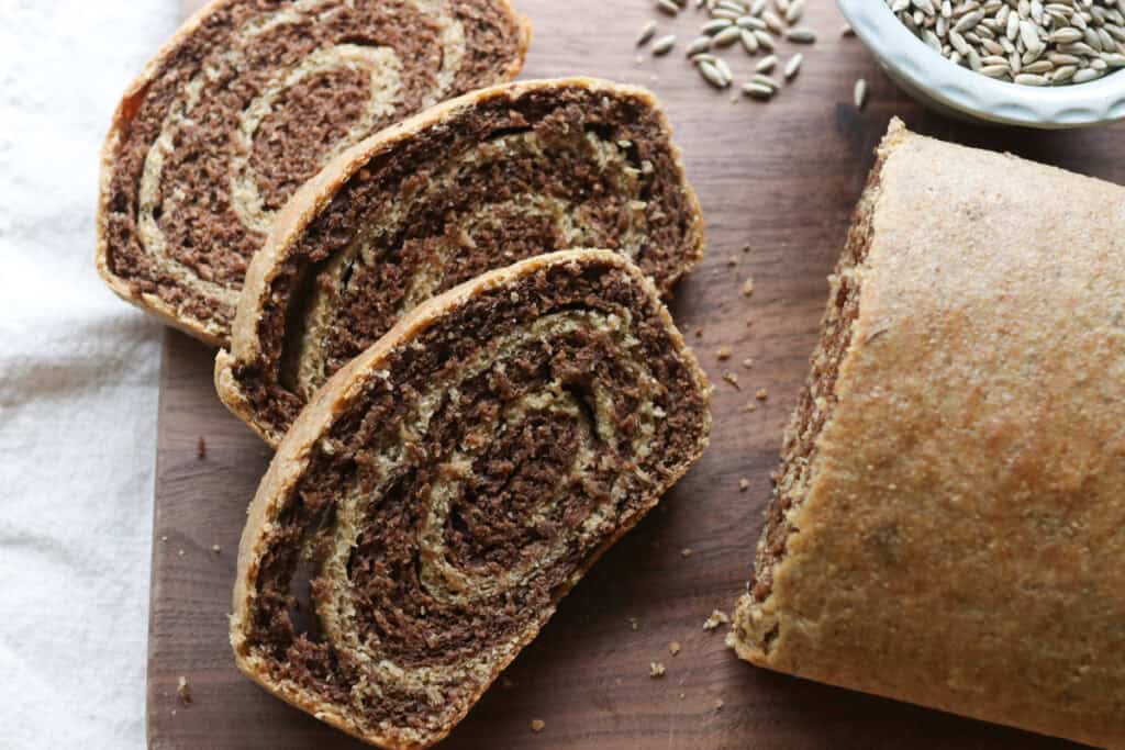 freshly milled marbled rye bread with 3 slices cut on a wooden board