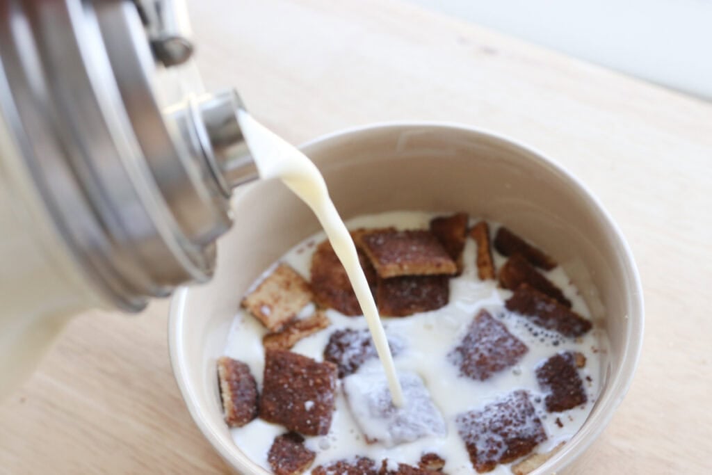 pouring milk into a bowl of Homemade Fresh Milled Cinnamon Toast Crunch Cereal