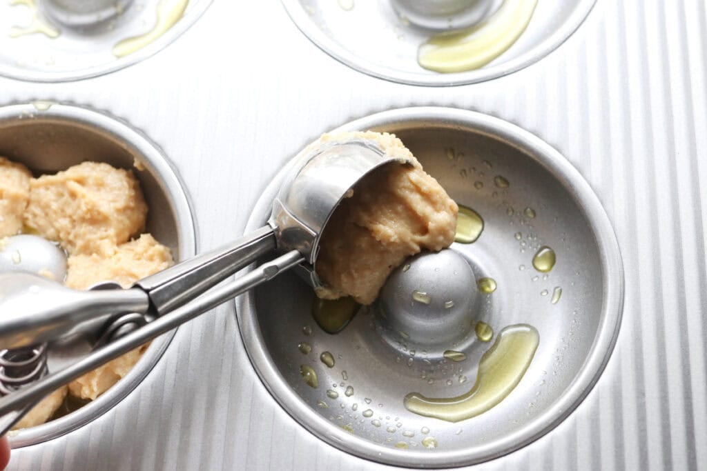 scooping fresh milled donut batter into a donut pan 