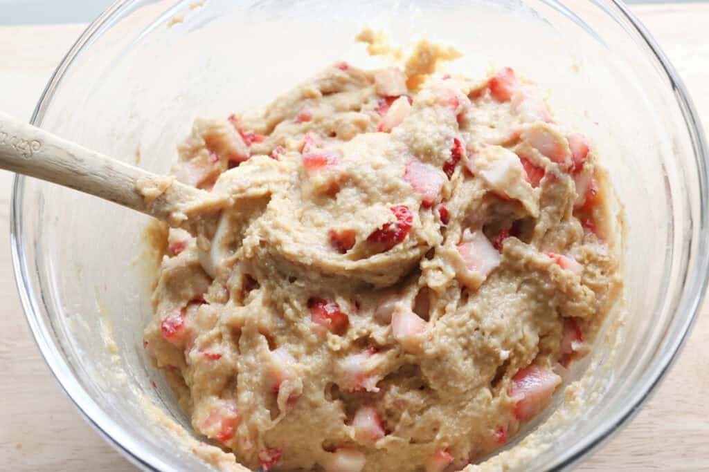 Freshly milled glazed strawberry bread batter in a glass bowl with a spatula