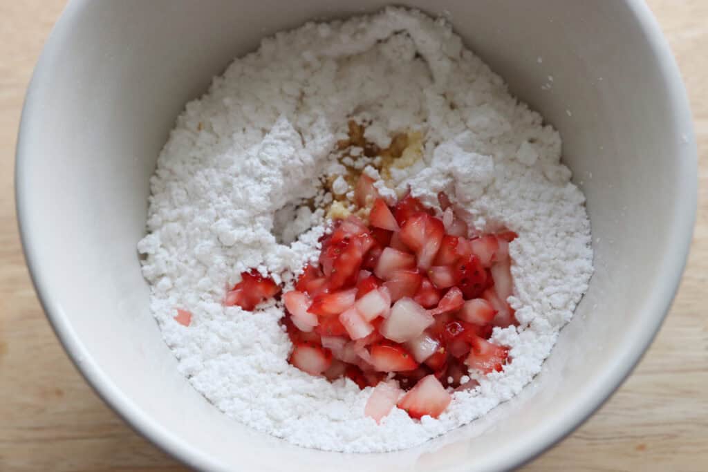 powdered sugar and strawberries in a bowl to make the glaze for freshly milled glazed strawberry bread
