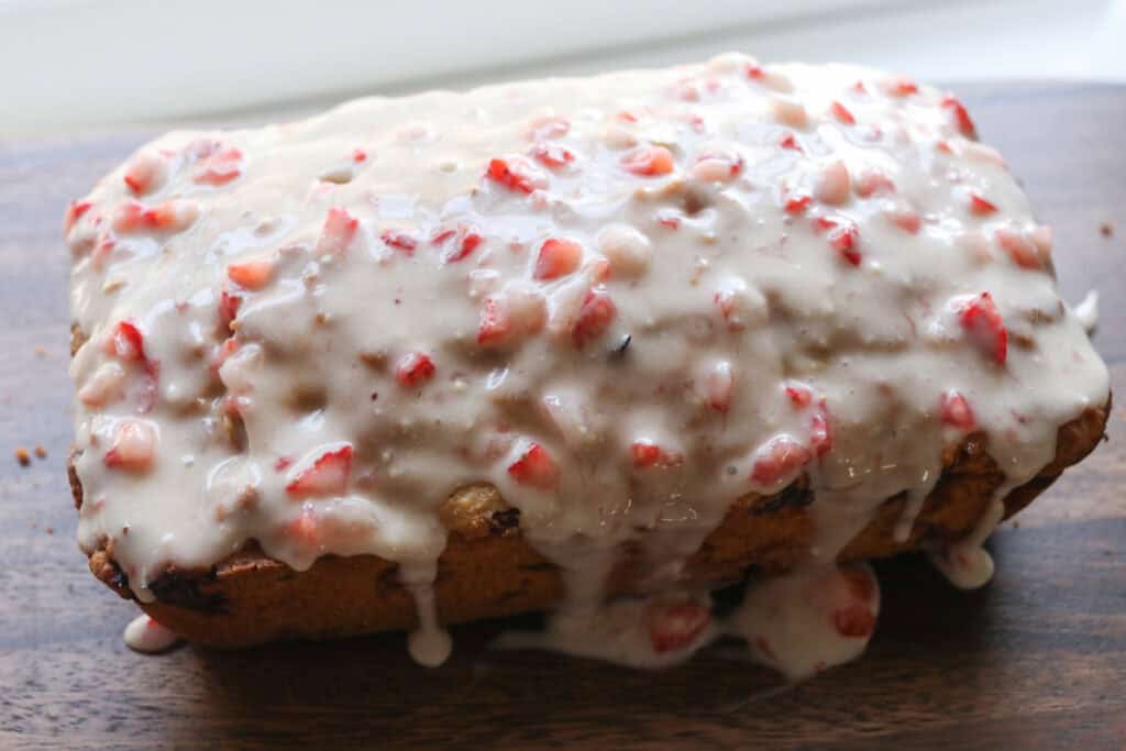 Freshly milled glazed strawberry bread on a wooden butter with chopped strawberries on top
