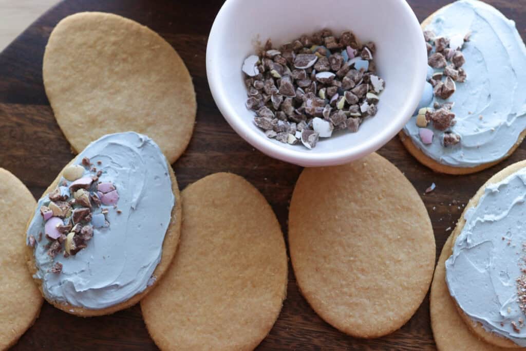 Fresh milled Easter egg sugar cookies and a white bowl with crushed chocolate eggs in it
