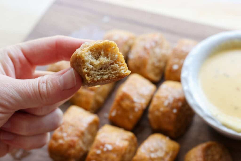 holding a Fresh Milled Soft Pretzel Bite that has a bite taken out of it