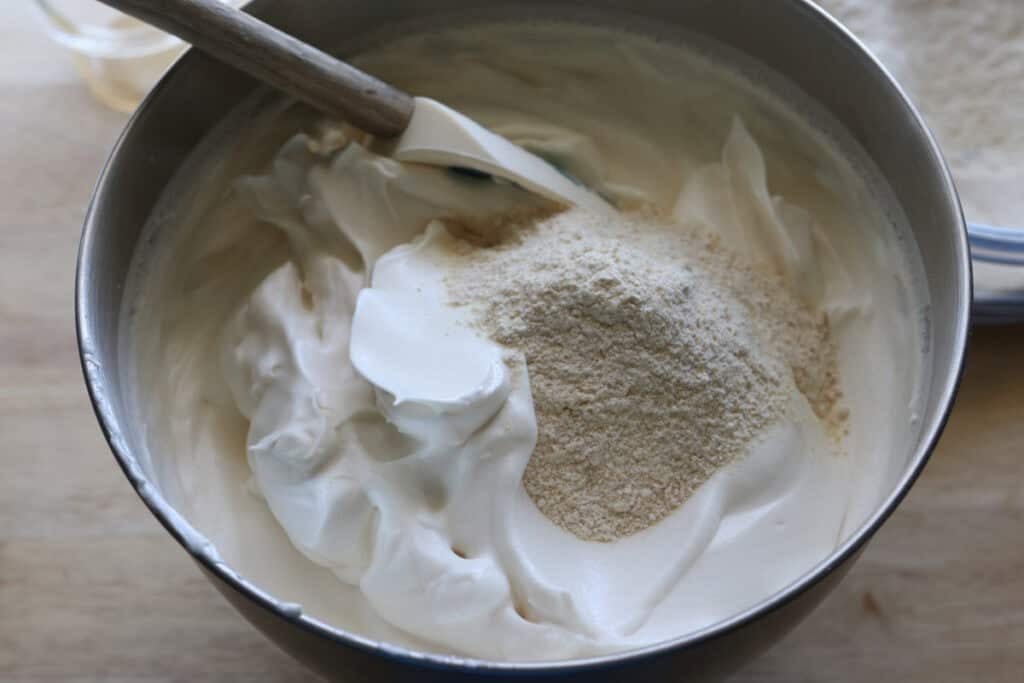 Folding the flour and sugar into the whipped egg whites to make freshly milled angel food cake