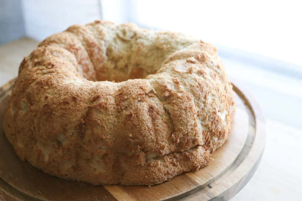 A freshly milled angel food cake on a wooden stand