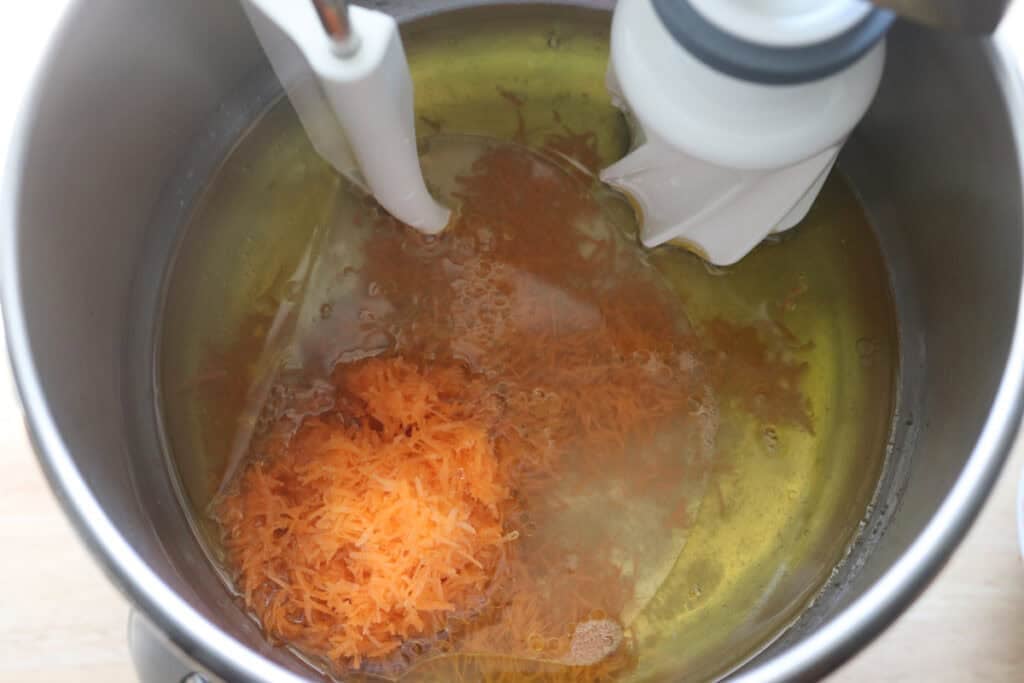 Shredded carrots, oil, and honey in a mixing bowl to make Fresh milled carrot cake cinnamon rolls