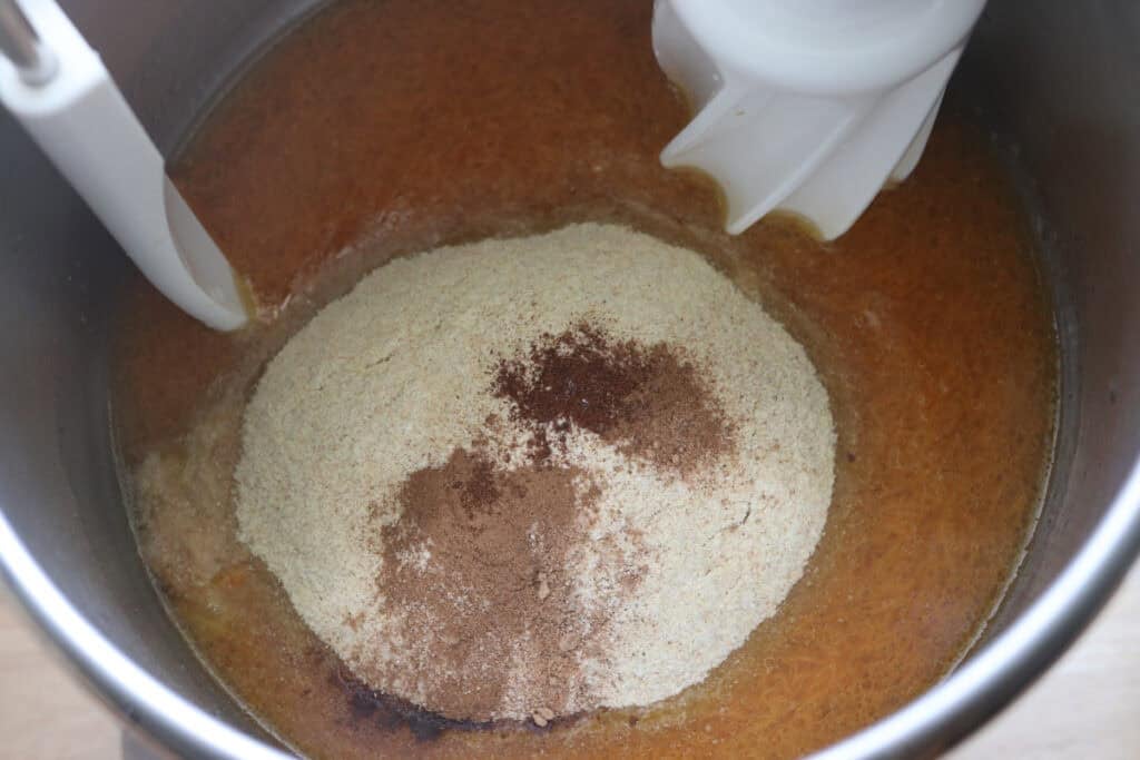 Flour and spices added to a bowl to make Fresh milled carrot cake cinnamon rolls