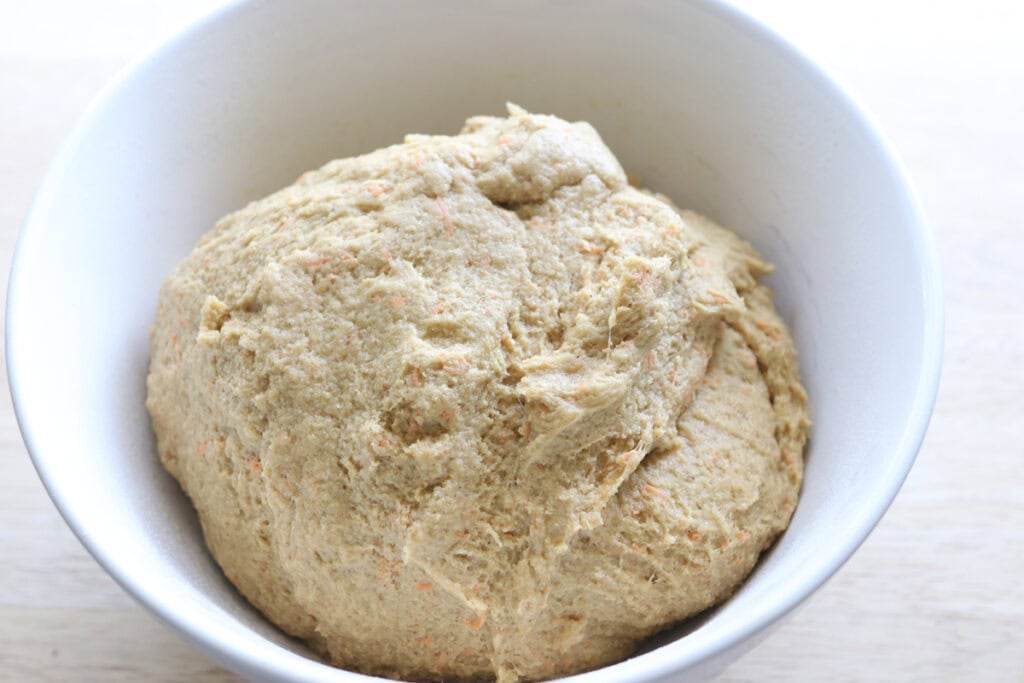 Fresh milled carrot cake cinnamon roll dough in a white bowl