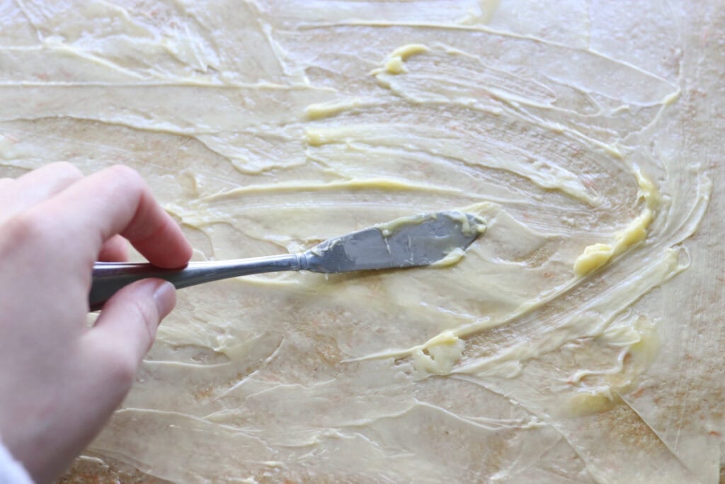 spreading butter onto Fresh milled carrot cake cinnamon roll dough