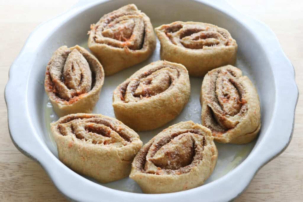 Fresh milled carrot cake cinnamon rolls in a dish rising
