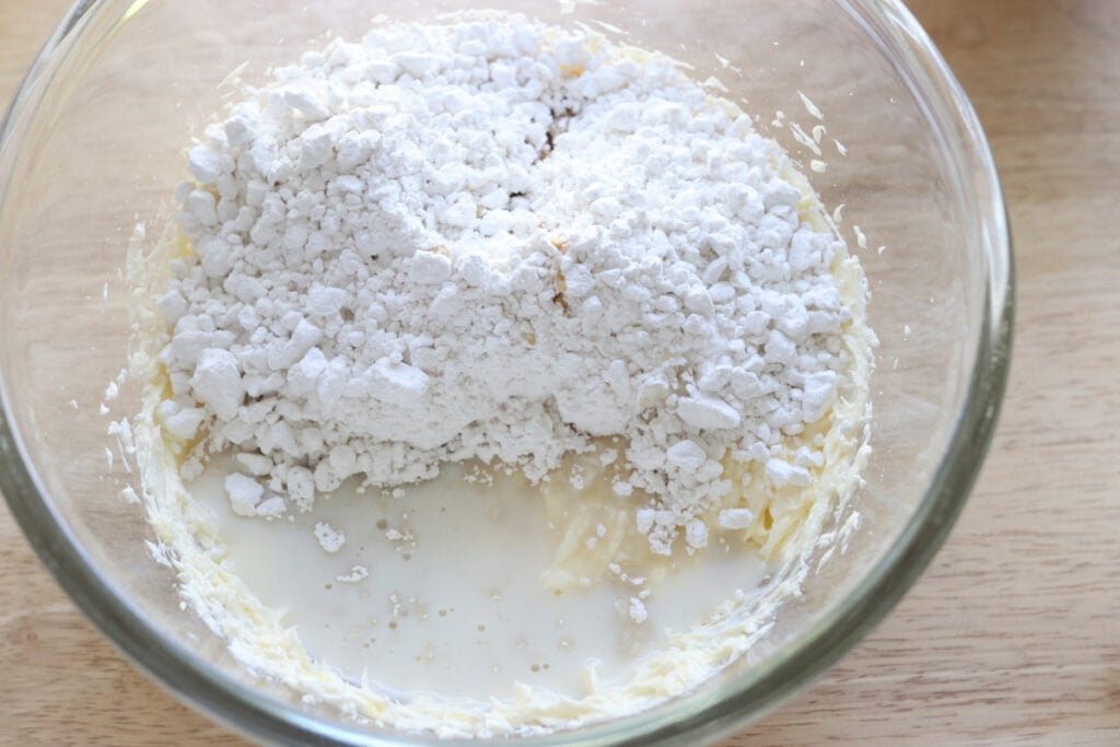 Powdered sugar and butter in a bowl to make the icing for Fresh milled carrot cake cinnamon rolls