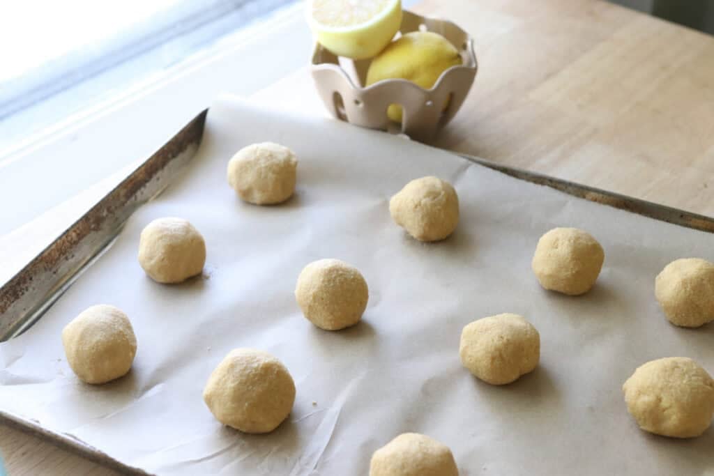 Fresh milled glazed lemon cookie dough scooped into balls on a baking sheet