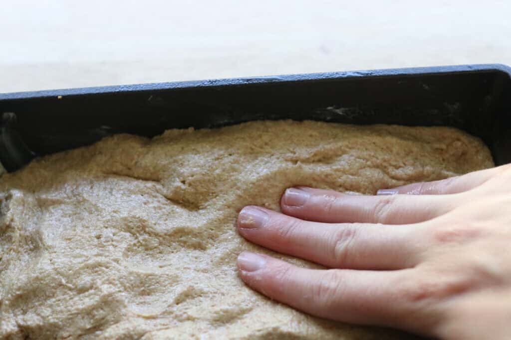 Pressing Freshly milled einkorn sandwich dough into a loaf pan 