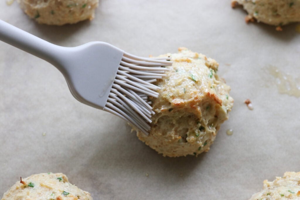 brushing a Freshly Milled Parmesan Chive Drop Biscuit with melted butter
