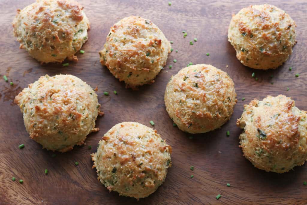 Easy Freshly Milled Parmesan Chive Drop Biscuits on a wooden cutting board with chives sprinkled on top