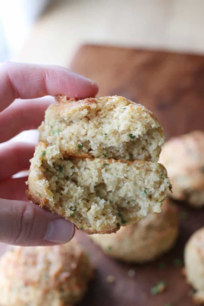 someone holding a Freshly Milled Parmesan Chive Drop Biscuit cut in half